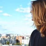 A woman standing on a rooftop, gazing over Saint Petersburg's urban skyline on a clear, sunny day.